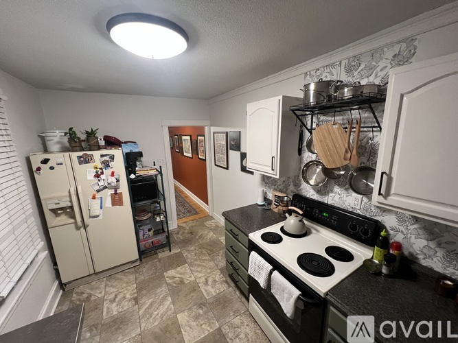 A kitchen with a black stove top and a refrigerator with magnets and notes on it.