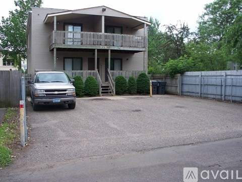 A silver car is parked in front of a two-story apartment building.