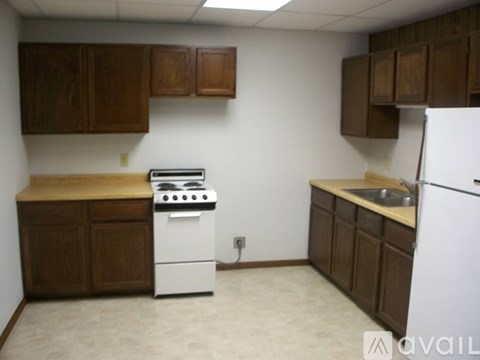 A kitchen with brown cabinets and a white stove and refrigerator.