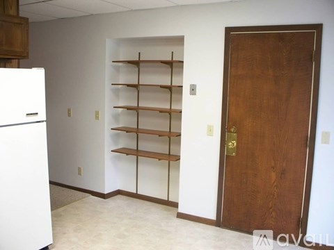 A kitchen with a white fridge and a wooden door.