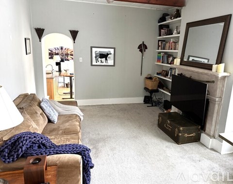 A living room with a couch, a fireplace, and a painting of a cow.