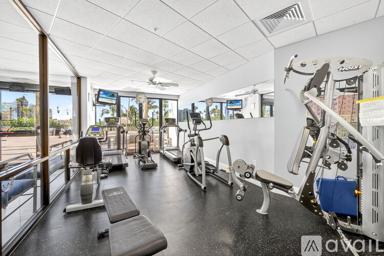 A gym with a variety of equipment including a treadmill, a stationary bike, and a rowing machine.