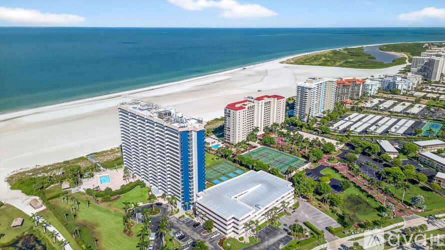 A beachfront resort with a large swimming pool and several buildings.
