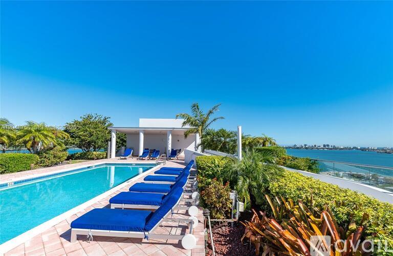 A pool with sun loungers and a white building in the background.