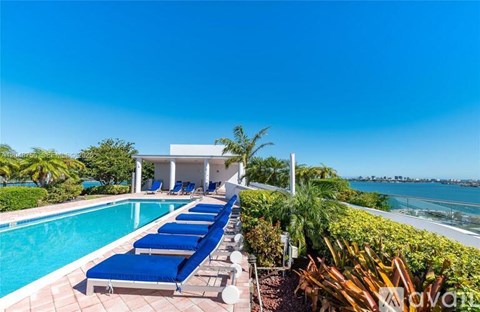 A pool with sun loungers and a white building in the background.