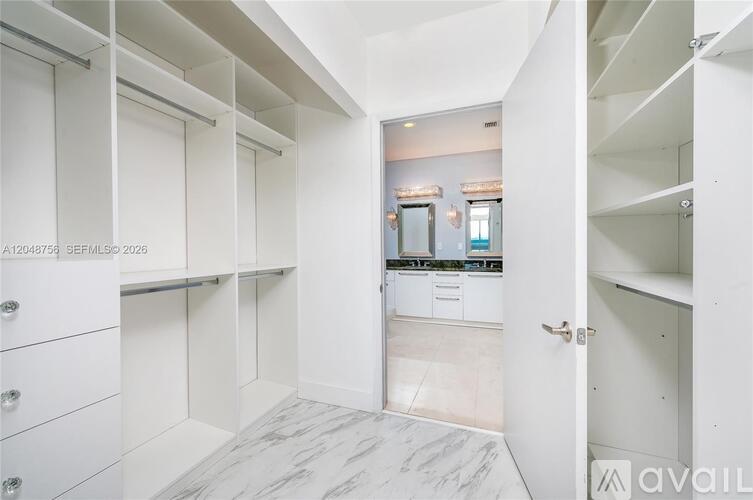 A spacious kitchen with white cabinets and a marble floor.