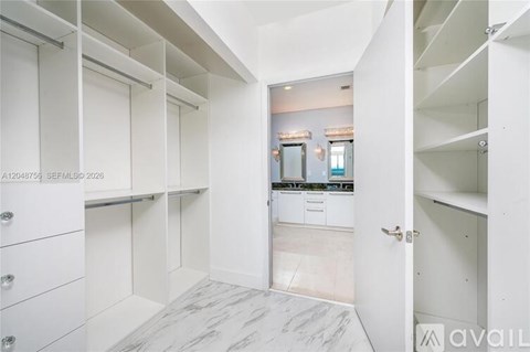 A spacious kitchen with white cabinets and a marble floor.