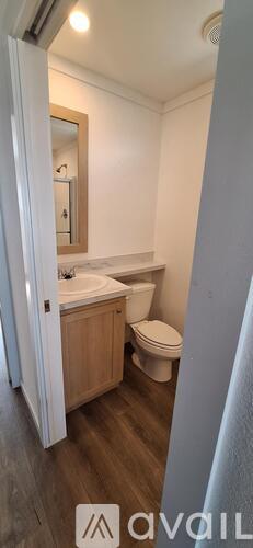 A bathroom with a toilet, sink, and mirror.