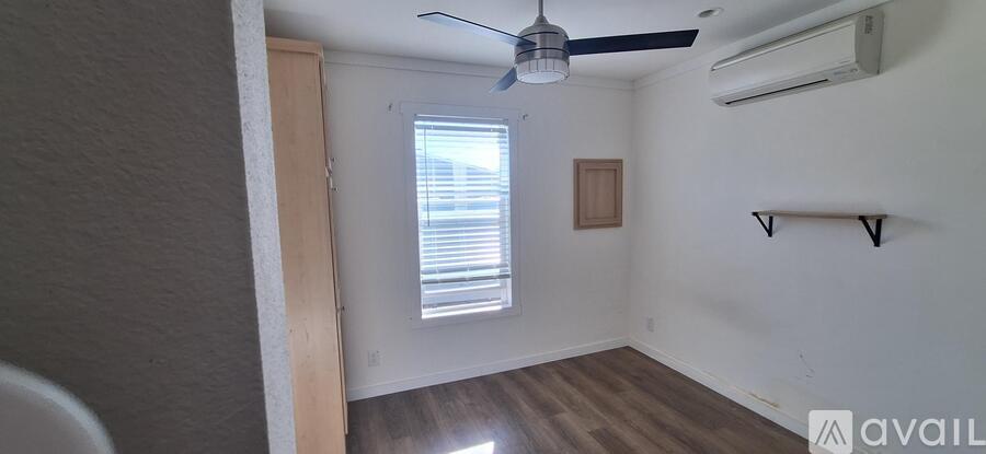A room with a ceiling fan and a window with blinds.