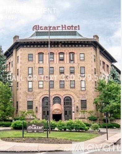The Alkazar Hotel is a large, historic building with a green lawn in front.