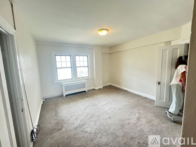 A person is standing in a room with a window and a radiator.