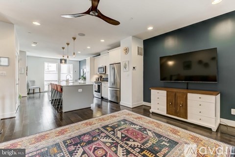 A living room with a rug on the floor and a ceiling fan.