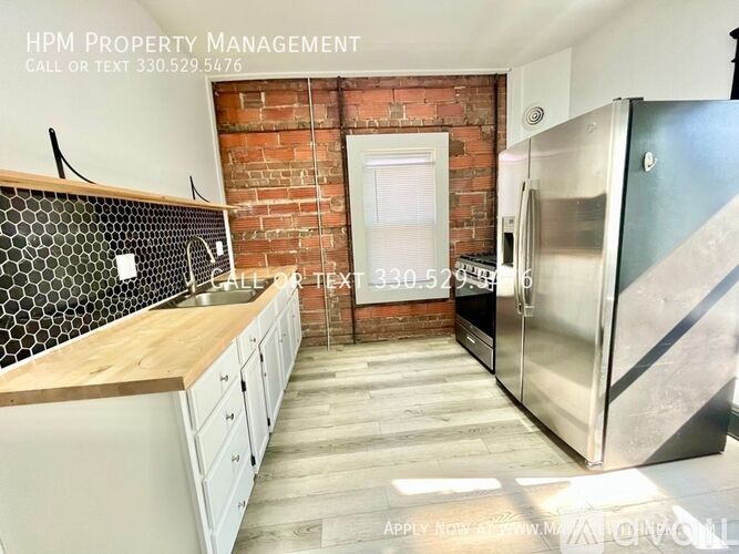 A kitchen with a brick wall and a refrigerator.