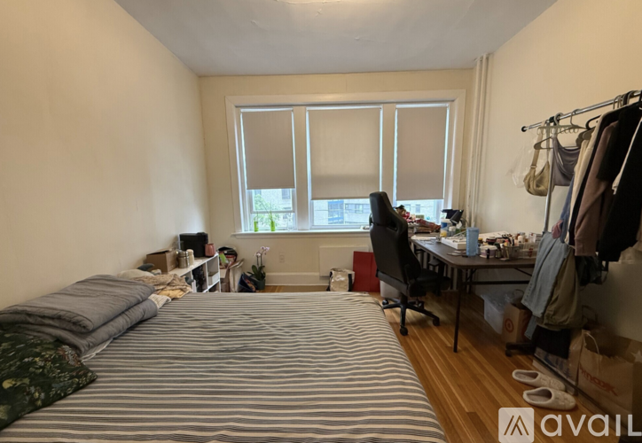 A bedroom with a bed, desk, and window.