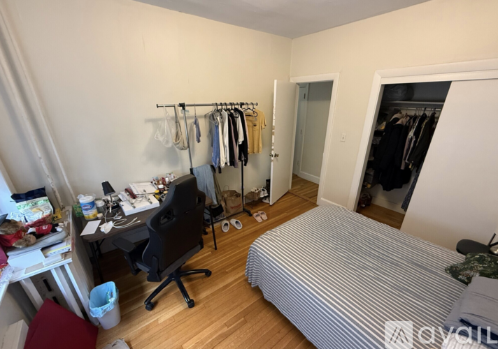A bedroom with a bed, desk, chair, and closet.