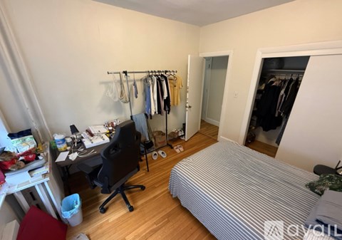 A bedroom with a bed, desk, chair, and closet.