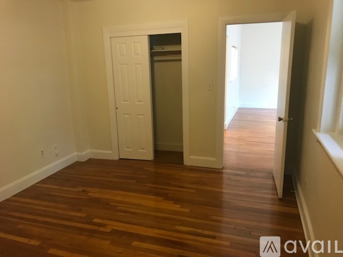 A room with wooden floors and two doors, one of which is open.