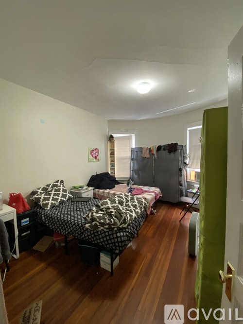 A bedroom with a bed, a desk, and a refrigerator.