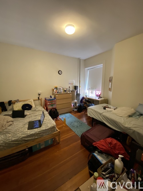 A bedroom with two beds and a desk with a laptop on it.