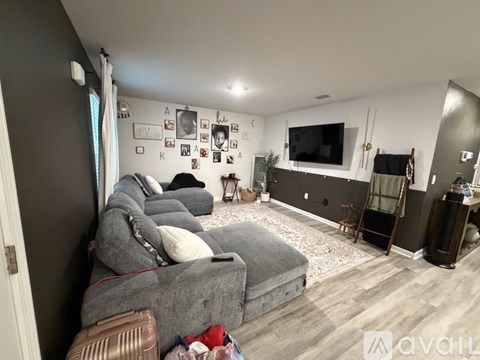 A living room with a grey couch and a TV on the wall.
