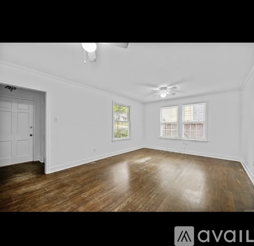 A spacious room with wooden floors and white walls.