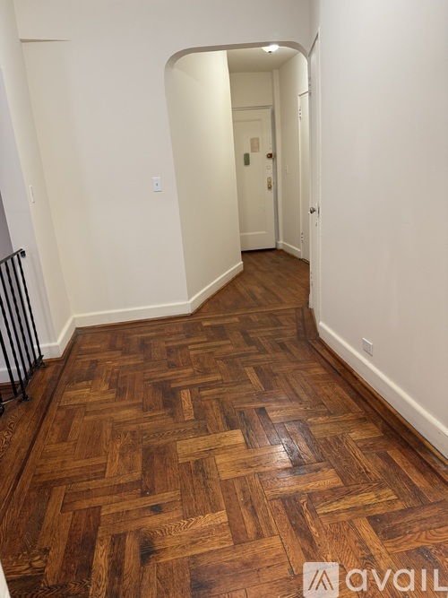 A hallway with a wooden floor and white walls.