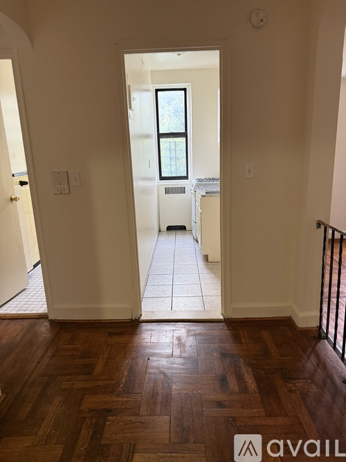 A hallway with a wooden floor and a doorway leading to another room.