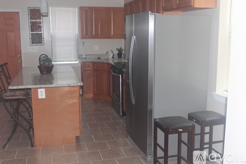 A kitchen with a refrigerator, stove, and bar stools.