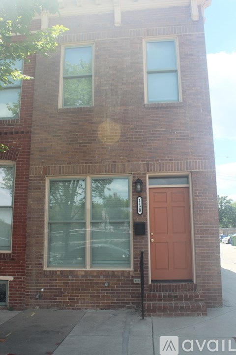 A brick building with a red door and a window reflecting the building.