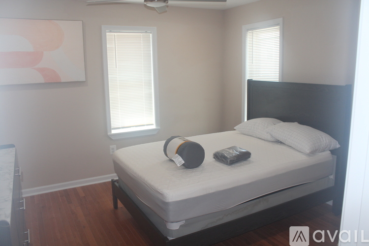 A bedroom with a bed, a fan, and a painting on the wall.