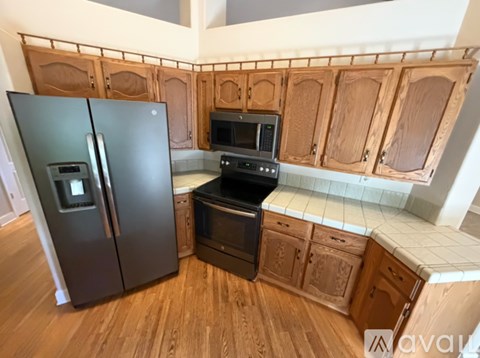 A kitchen with wooden cabinets and a black fridge.