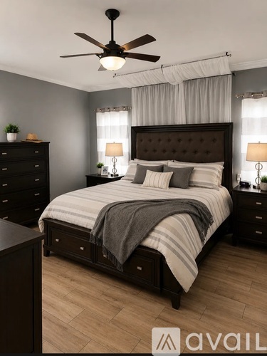 A bedroom with a large bed, a ceiling fan, and two lamps.