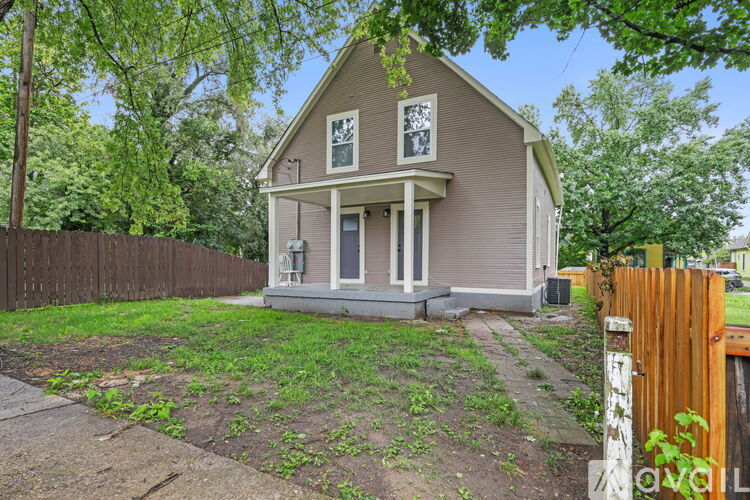 A house with a brown fence and green trees in the background.