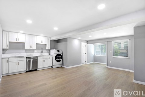 A kitchen with white cabinets and a wooden floor.