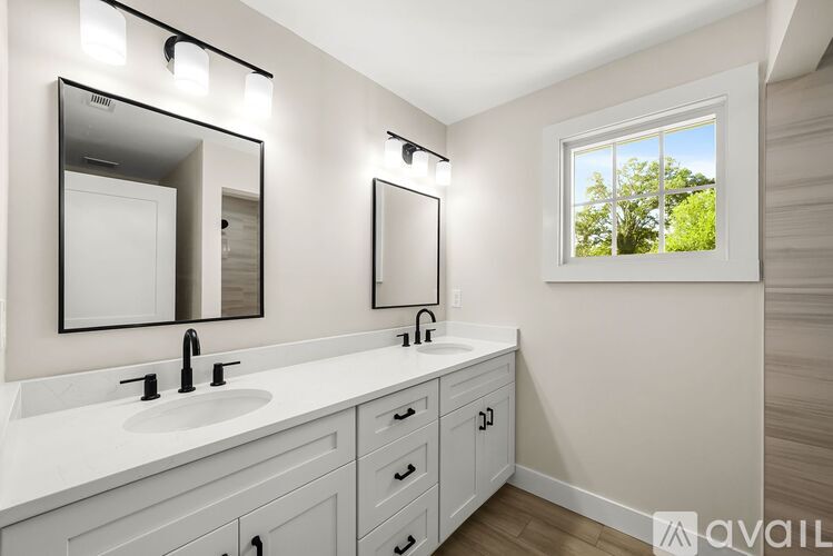 A bathroom with a large mirror and a window showing trees outside.