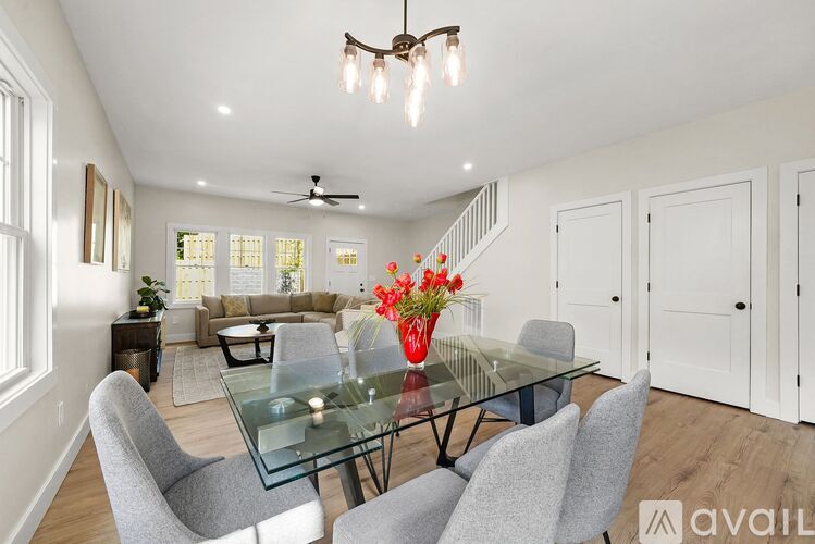 A modern dining room with a glass table and grey chairs.