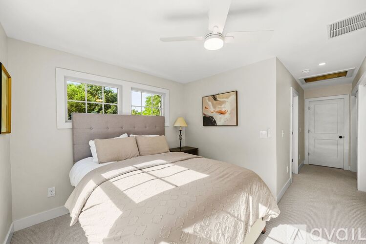 A bedroom with a large bed and a window letting in natural light.