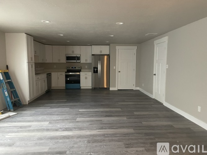 A spacious kitchen and living room with a grey floor and white walls.