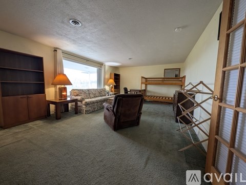 A living room with a brown couch, a chair, a lamp, and a television.