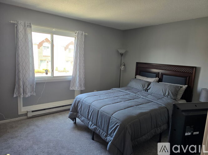 A bedroom with a bed, nightstand, and window.