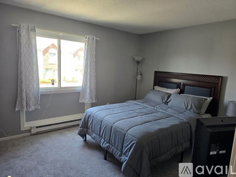 A bedroom with a bed, nightstand, and window.
