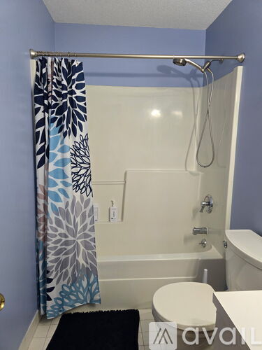 A bathroom with a blue shower curtain and a white toilet.