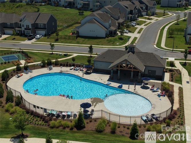 A large swimming pool surrounded by a fence with people enjoying the water.