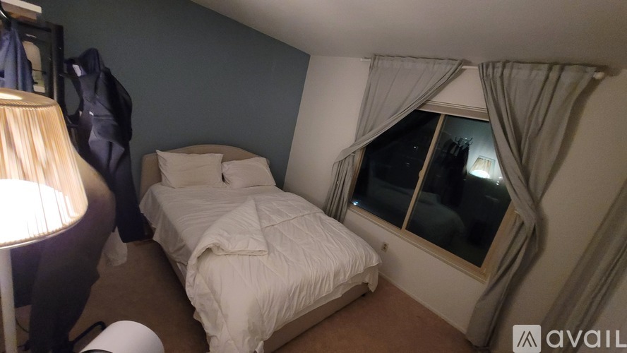 A bedroom with a bed, nightstand, and window.
