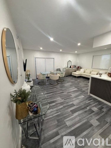 A living room with a grey carpet and a glass table.