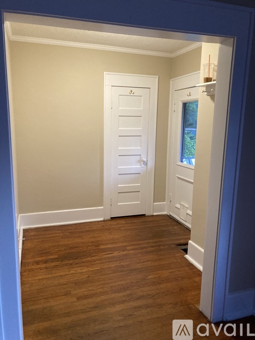 A hallway with a white door and a window.