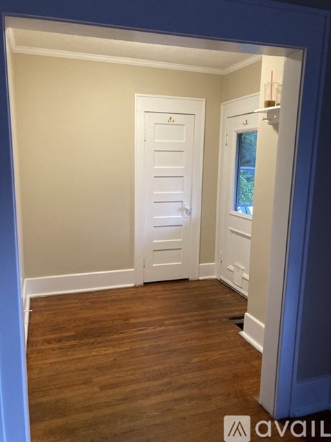 A hallway with a white door and a window.