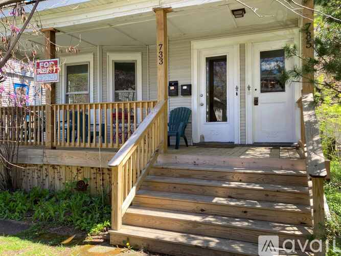 A house with a porch and a sign that says "For Sale".