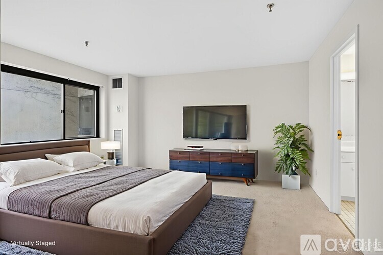 A bedroom with a large bed, a television, and a plant.