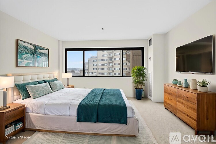 A bedroom with a large bed, a dresser, and a window overlooking a building.